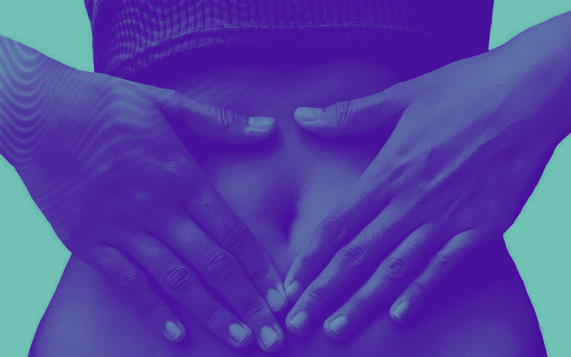 Imagem de mulher com as mãos em forma de coração sobre o estômago