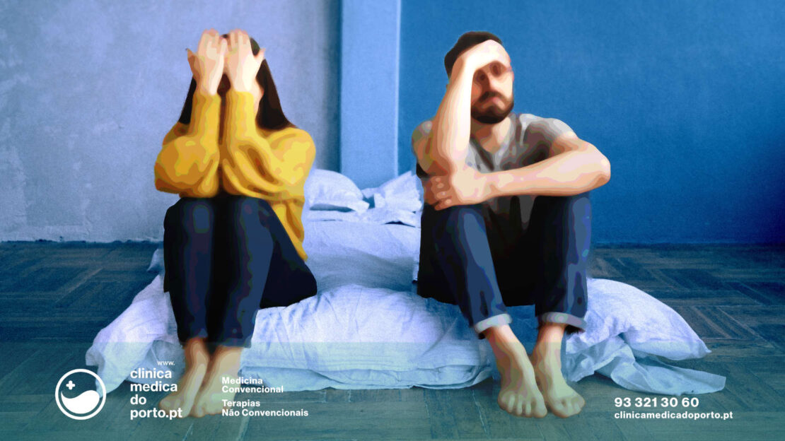 Um homem e uma mulher, casal sentados na cama em com as mãos no rosto em sinal de preocupação